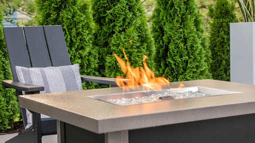 A modern outdoor fireplace with a fire burning in it.