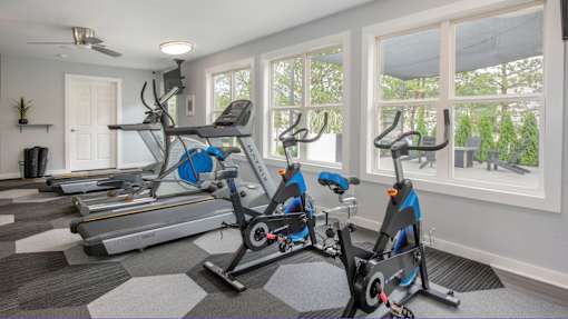 A home gym with a treadmill and two stationary bikes.