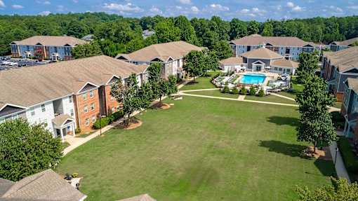 A large grassy area surrounded by houses with a pool in the middle.