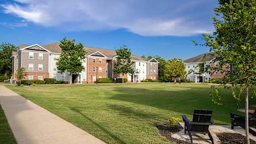 A row of apartment buildings with a green lawn in front.