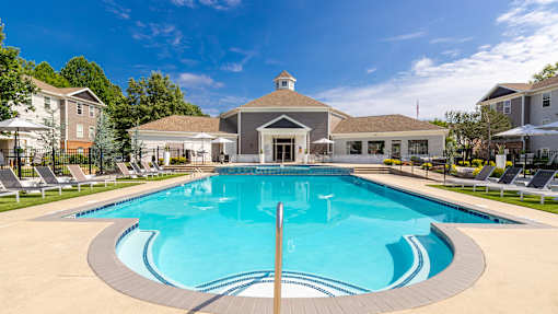 A large swimming pool in front of a building with a gazebo.