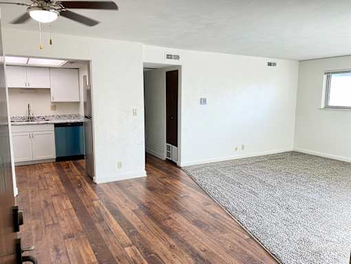 A room with a ceiling fan and wooden flooring.