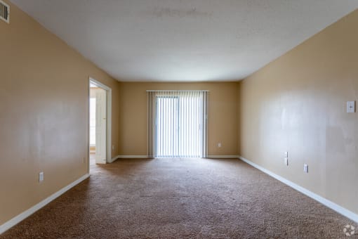 the spacious living room of an empty house with a large window