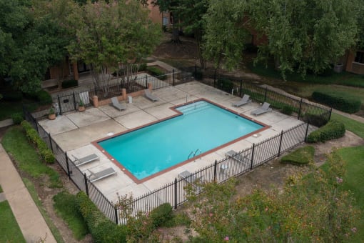 a pool with a fence around it in a yard with trees