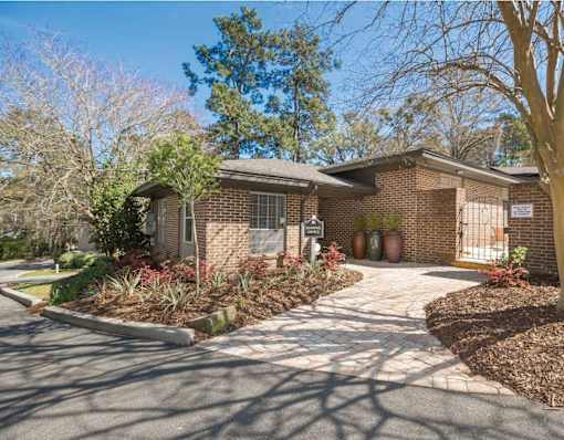 A house with a driveway and a tree in front.