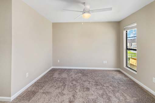 A room with a ceiling fan and carpeted floor.