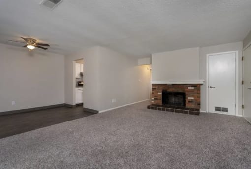 an empty living room with a fireplace and a ceiling fan