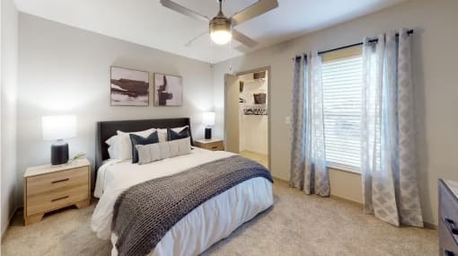 a bedroom with a large window and a ceiling fan