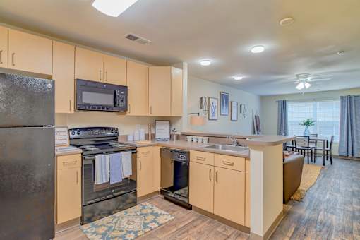 A kitchen with wooden cabinets and a black refrigerator.