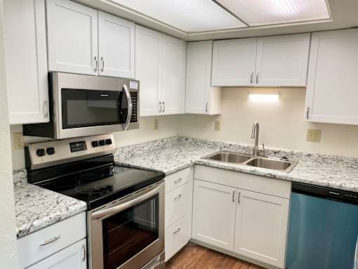 A kitchen with white cabinets and a black stove top oven.