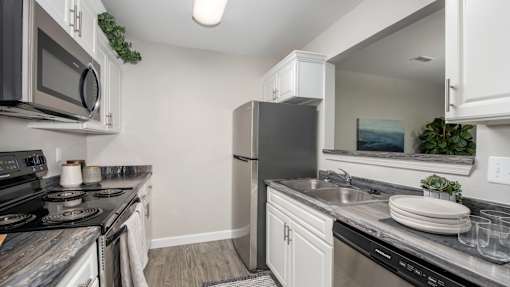 A kitchen with a black refrigerator and a black stove top oven.