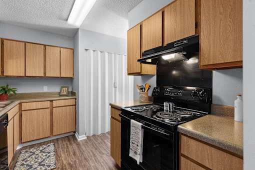 A kitchen with a black stove top oven and wooden cabinets.