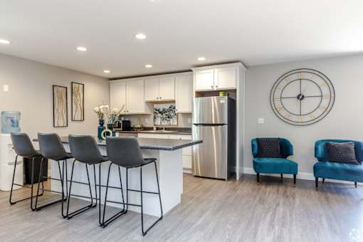 A modern kitchen with a bar area and a clock on the wall.