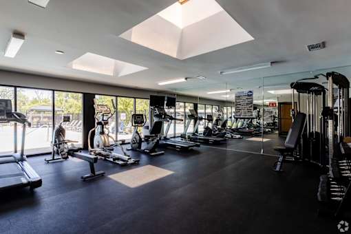 A gym with a variety of equipment including treadmills, weights, and exercise machines.
