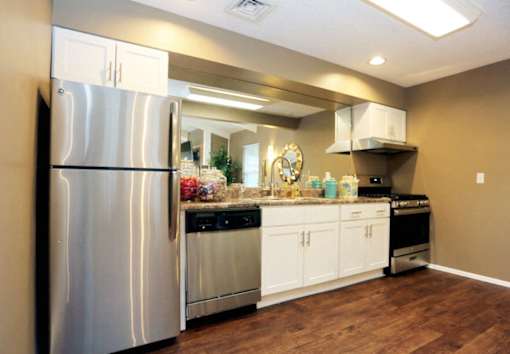 A modern kitchen with a stainless steel refrigerator and wooden flooring.