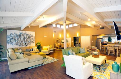 A living room with a white couch and a painting on the wall.