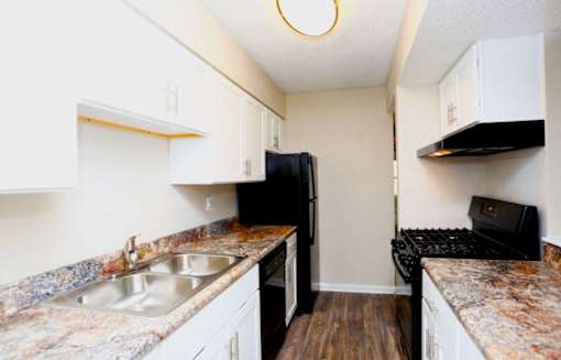 A kitchen with black appliances and granite countertops.