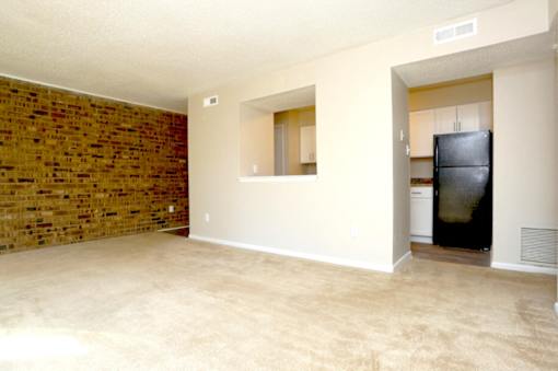 A room with a brick wall and a black fridge.