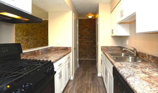 A kitchen with a black stove top oven and a marble counter top.