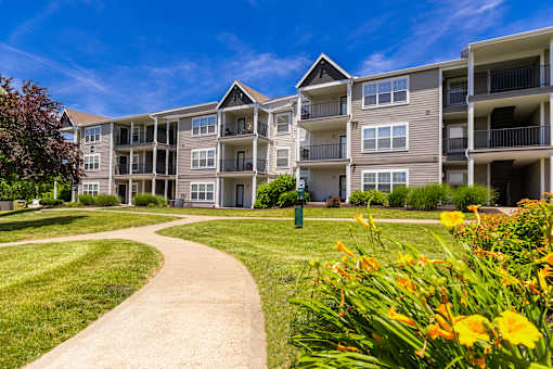 A sunny day at a residential apartment complex with a walkway and greenery.