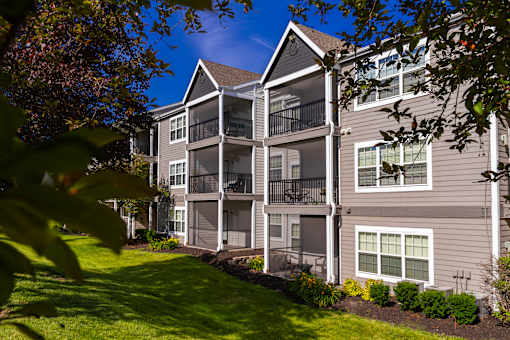 A large apartment building with a green lawn in front.