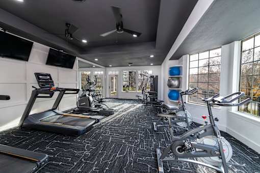 A spacious gym with treadmills, exercise bikes, and a television.