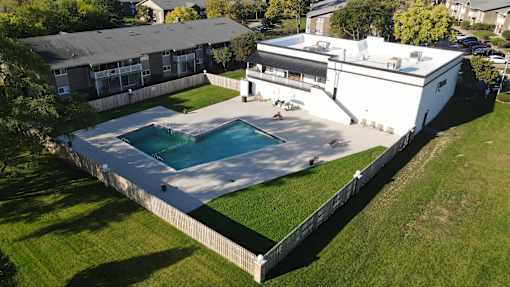 A swimming pool surrounded by a white fence and a white building with a black roof.