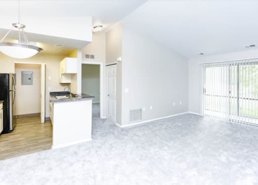 an empty living room and kitchen with a large window