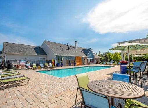 a swimming pool with chairs and tables around it