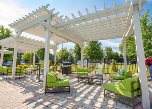 a patio with green chairs and tables under a white canopy