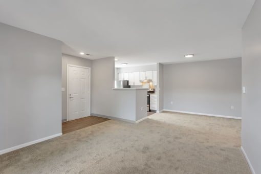 the living room and kitchen of an empty home with a carpeted floor