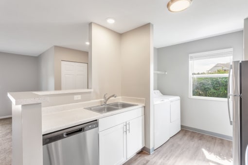 a white kitchen with a stainless steel sink and a window