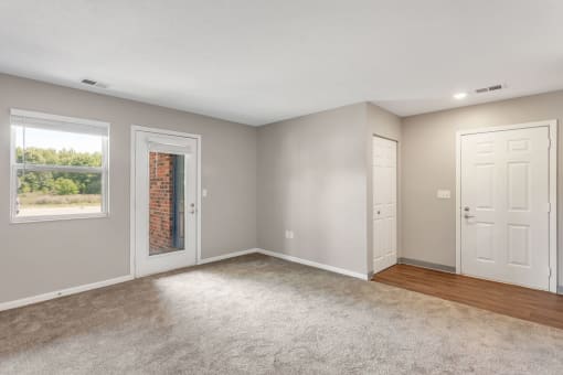 an empty living room with two doors and a window