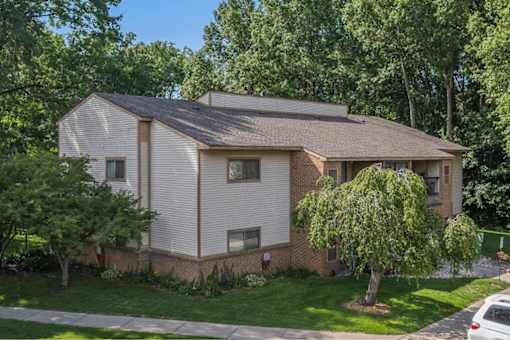 a white and brick house with a tree in the yard