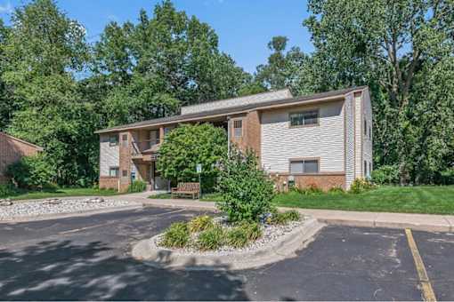 the front of a house with a parking lot and trees