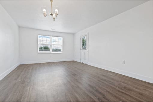 an empty living room with white walls and wood floors