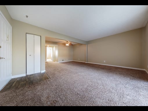 an empty living room with a closet and ceiling fan