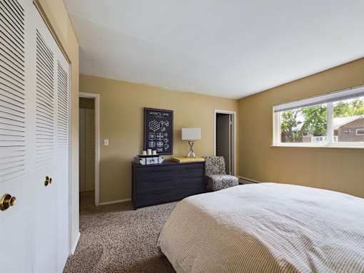 A bedroom with a bed, dresser, and window.