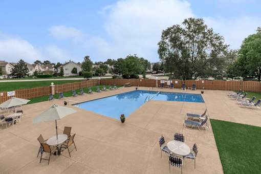 A large outdoor pool area with chairs and tables.