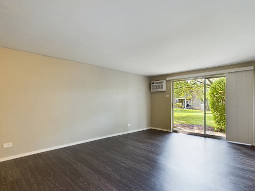 Empty room with a sliding glass door leading to a backyard.