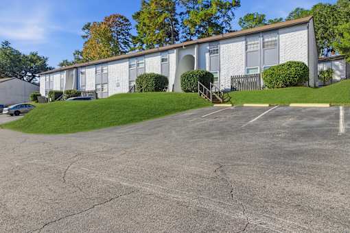 A white building with a parking lot in front.