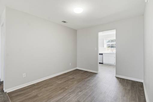 A room with light wood flooring and white walls.