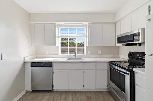 A kitchen with white cabinets and a window.