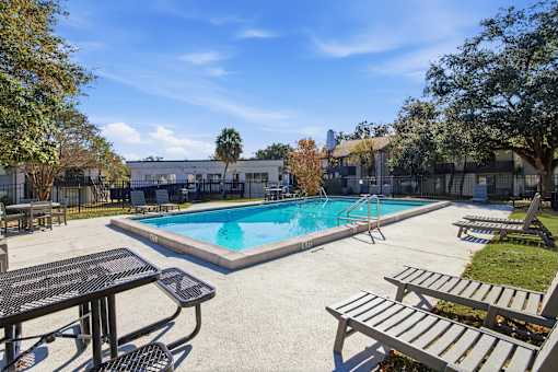 A pool surrounded by trees and a sunny sky.