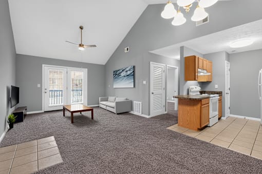 A spacious living room with a grey carpet and a ceiling fan.