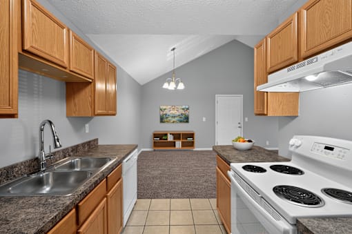 A kitchen with a white stove top oven and a white dishwasher.