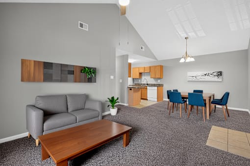 A living room with a grey couch, a wooden coffee table, and a dining table with chairs.