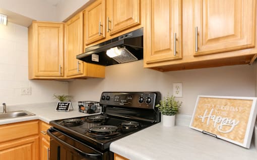 A kitchen with wooden cabinets and a black stove top oven.