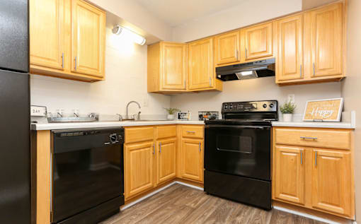 A kitchen with wooden cabinets and black appliances.