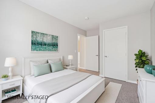 A bedroom with a large bed, two lamps, and a painting on the wall.